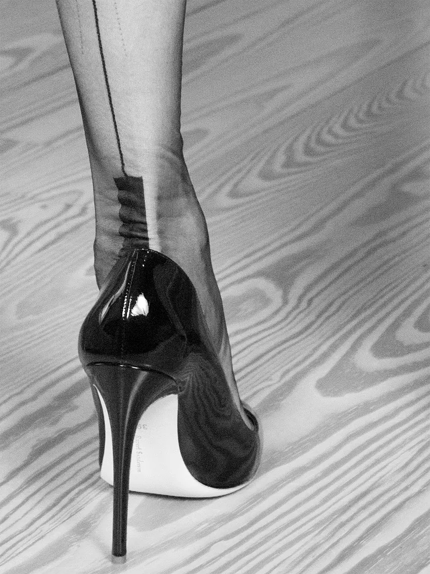 Detailaufnahme eines bestrumpften Beins mit Cuban Heel und schwarzen High Heels